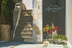 A staircase leading to a building with a sign reading "Agorastos Suites". There are flower pots with flowers on the steps. - Agorastos Suites (Thasos)