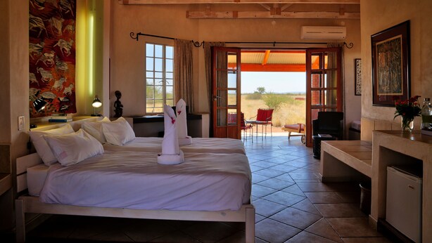 A hotel room with two beds, a desk, and a view of the outdoors. - Guest Farm Kiripotib (Windhoek)