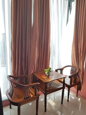 A dining area with a wooden table and chairs, a potted plant, and sheer curtains. - Khach San Gims (Ho Chi Minh City)