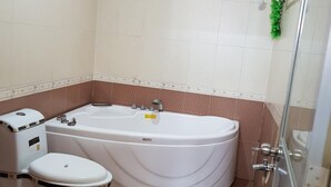 Een badkamer met een bad, toilet en douche.