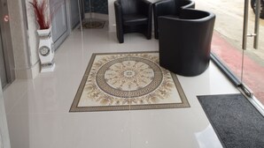 Um hall moderno com um tapete estampado, assentos pretos e uma porta de vidro que dá para o exterior.