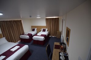 A hotel room with three beds, a desk, and a chair. - PremierLux Serviced Apartments (Ilford)