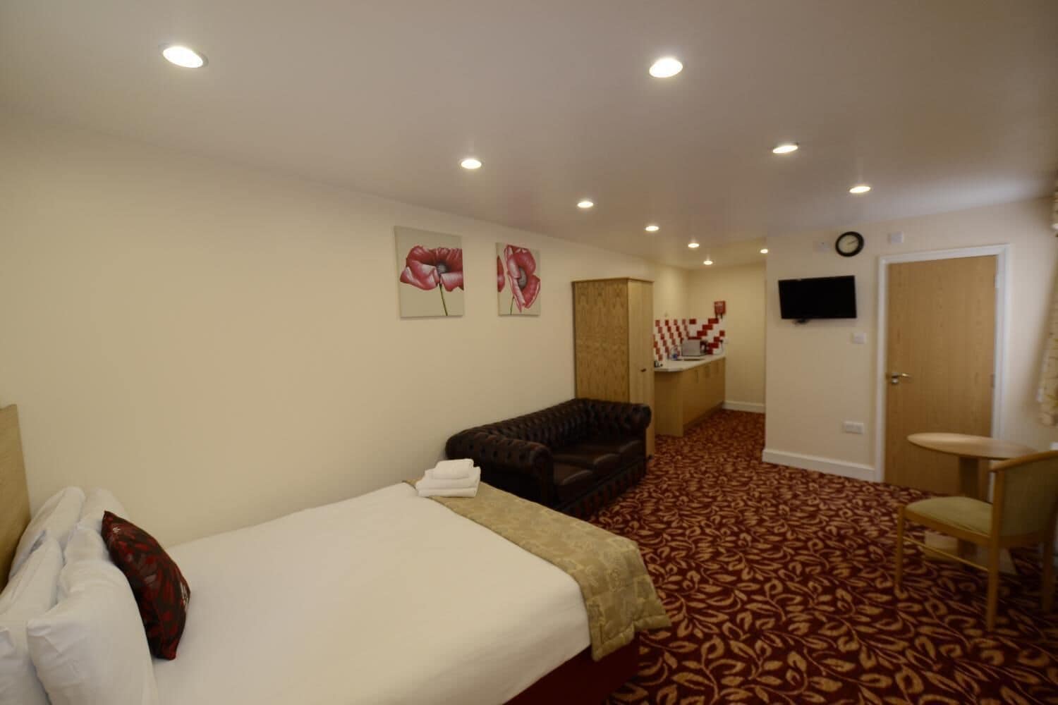 Una habitación de hotel con cama, sofá, escritorio con silla y televisor en la pared.