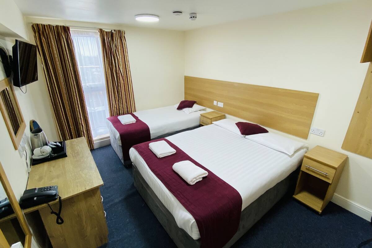 A hotel room with two beds, a desk with a telephone, and a TV mounted on the wall.