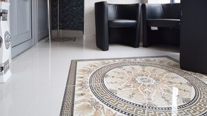Um lobby moderno com piso estampado, assentos pretos e uma grande janela.