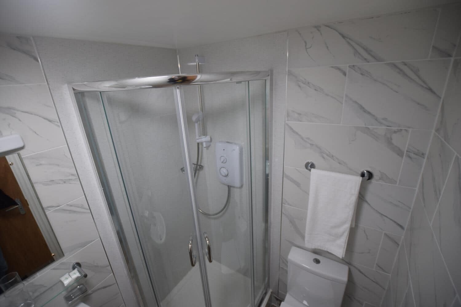A modern bathroom with a glass-enclosed shower, a toilet, and a sink.