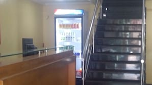 Un espace d’accueil avec un comptoir en bois, un distributeur automatique et un escalier.