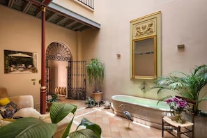 A spacious indoor area with a large bathtub, a sofa, and a dining table. - CH Apartments Rooftop Terrace (Seville)