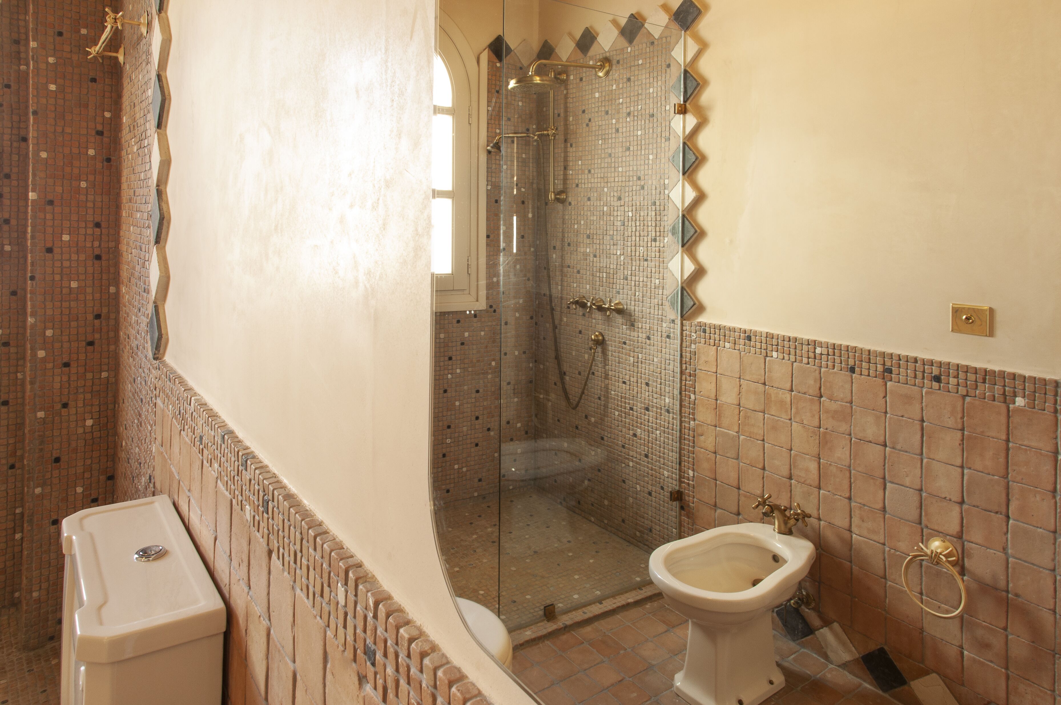 A bathroom with a shower, toilet, and bidet.