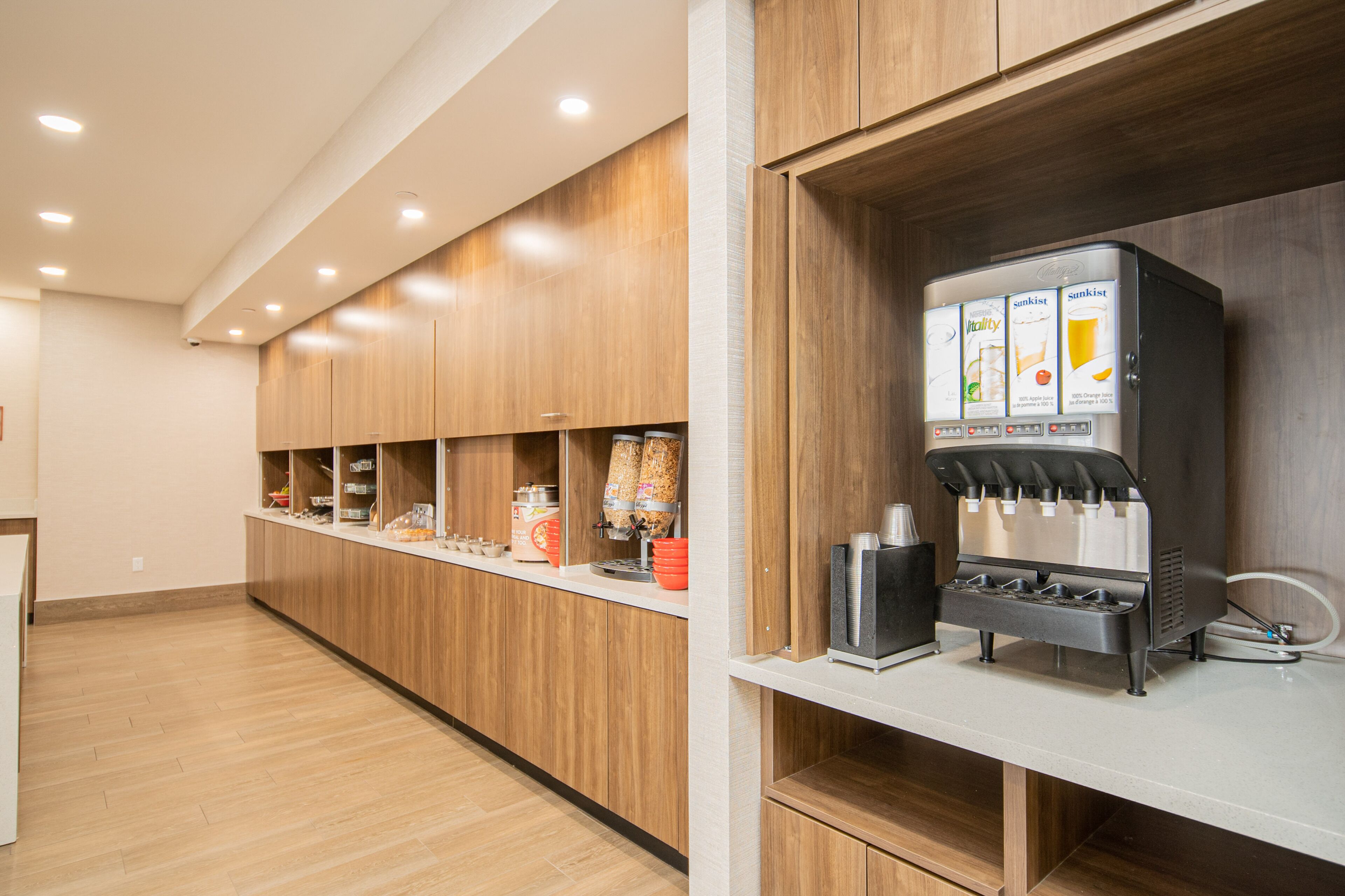 Una cocina moderna con armarios de madera, una cafetera de acero inoxidable y una encimera con diversos objetos.