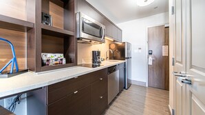 A modern kitchen with stainless steel appliances, wooden cabinets, and a built-in dishwasher. - TownePlace Suites by Marriott Brantford and Conference Centre (Brantford)