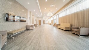 A spacious lobby with a long reception desk, multiple seating areas, and large windows providing natural light. - TownePlace Suites by Marriott Brantford and Conference Centre (Brantford)