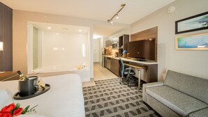 Una habitación de hotel con cama, sofá, escritorio, kitchenette y baño.