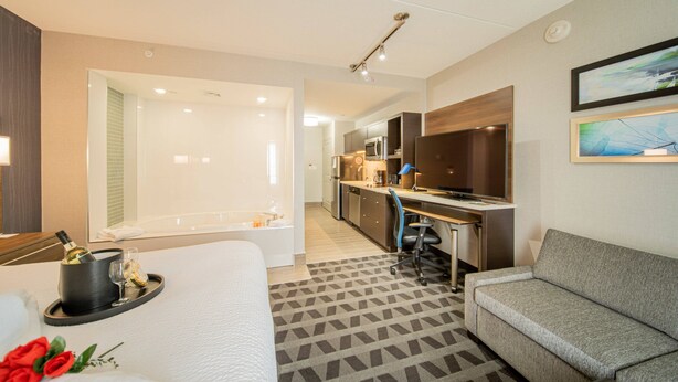 A hotel room with a bed, a sofa, a desk, a kitchenette, and a bathroom. - TownePlace Suites by Marriott Brantford and Conference Centre (Brantford)
