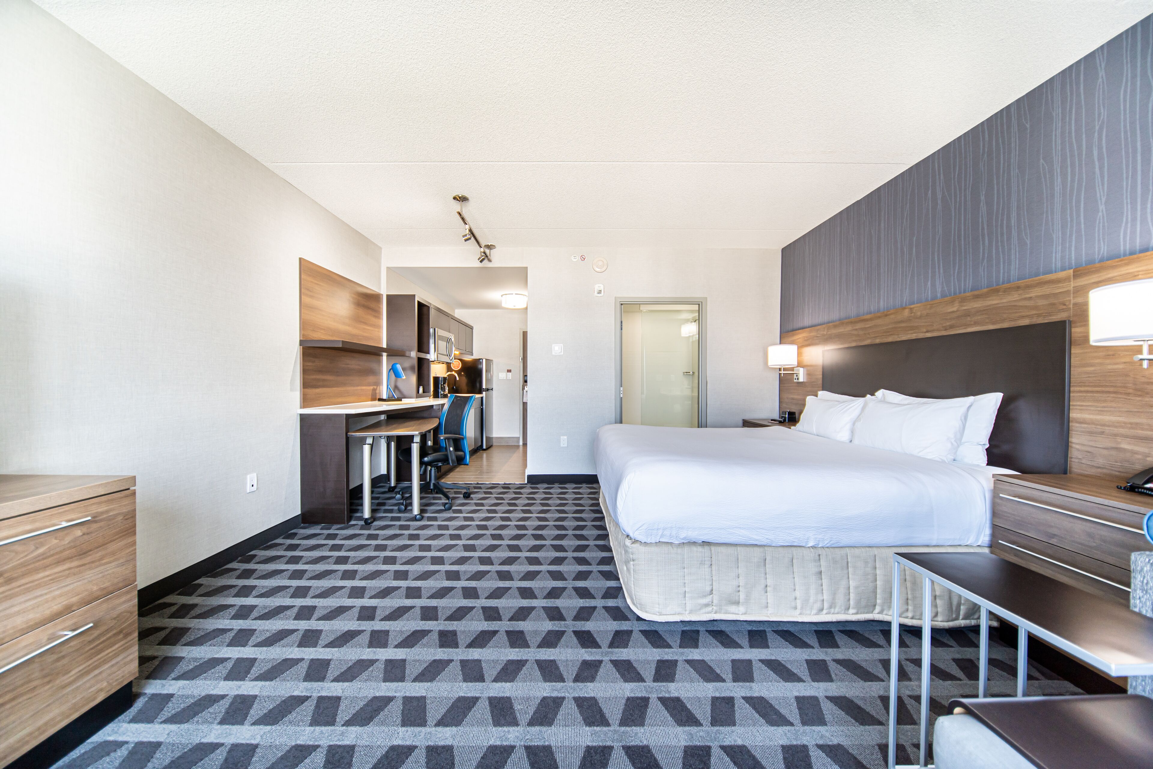 A hotel room with a bed, desk, chair, and a small table.