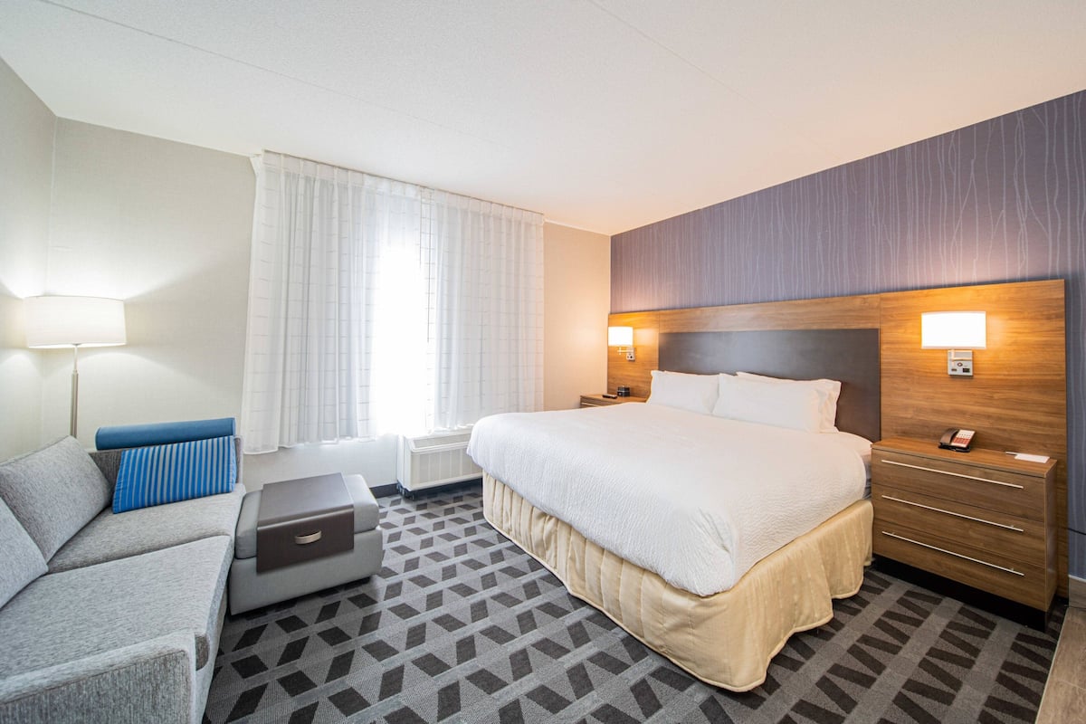 A hotel room with a large bed, a sofa, a desk, and a dresser.