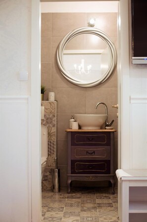 A bathroom with a round mirror, a sink, and a cabinet. - Mama's and Papa's Luxury Rooms (Split)