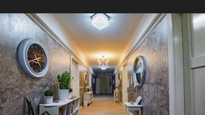 A hallway with a chandelier, round mirrors, and potted plants. - Mama's and Papa's Luxury Rooms (Split)