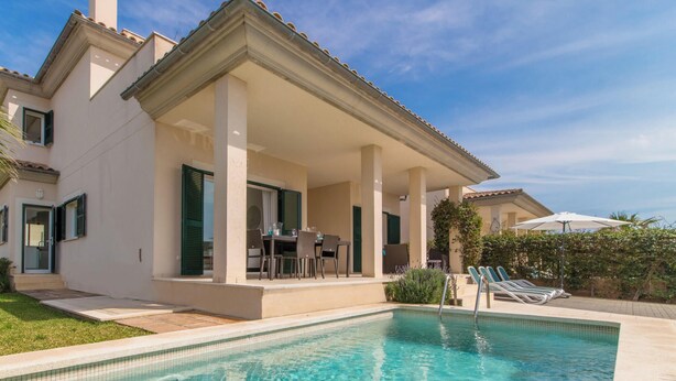 Une maison à deux étages avec une piscine, un espace salon extérieur et une terrasse couverte.