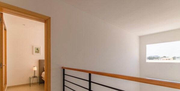 A staircase with a wooden handrail and a view of a bedroom with a bed and a bedside table. - Bella Mar 1, Villa 5StarsHome Mallorca (Alcúdia)
