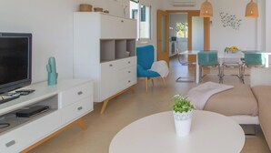 Un salon moderne avec un canapé, un téléviseur et un coin repas.