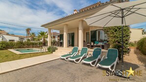 Un espace piscine avec des chaises longues et un patio couvert.