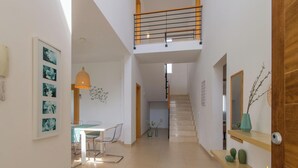 Un intérieur moderne comprenant un coin repas, un escalier et un couloir menant à une chambre.
