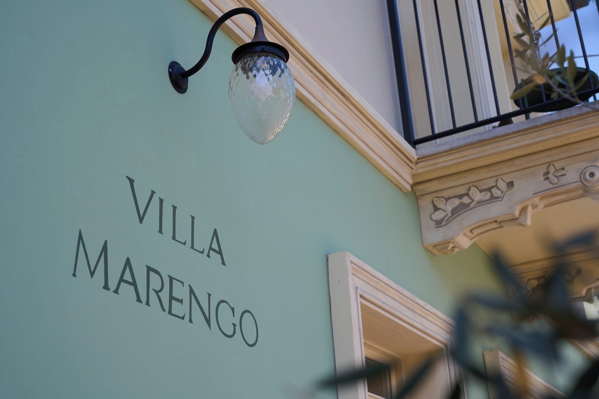 Un muro con il testo "VILLA MARENGO" e un lampadario decorativo.