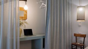 Une pièce comprenant un lit, un bureau avec un ordinateur portable, une chaise et un luminaire suspendu.