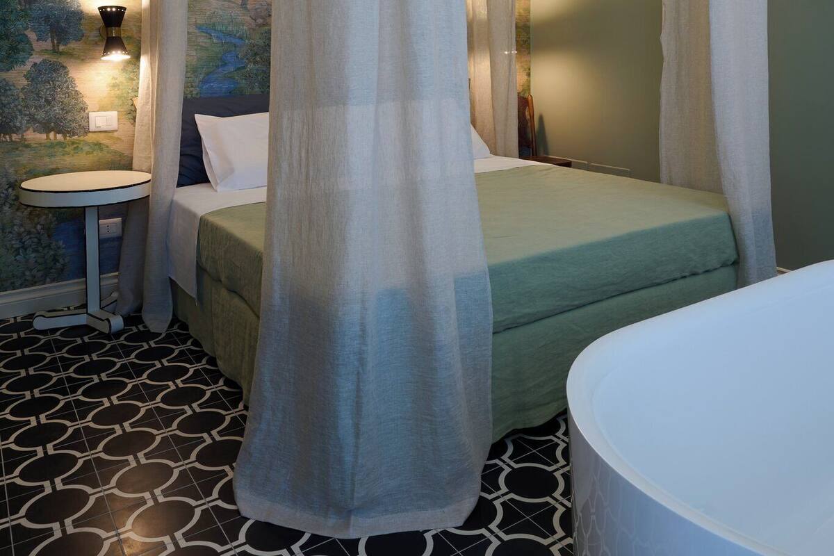 A bedroom with a canopy bed, a bedside table, and a wall mural.