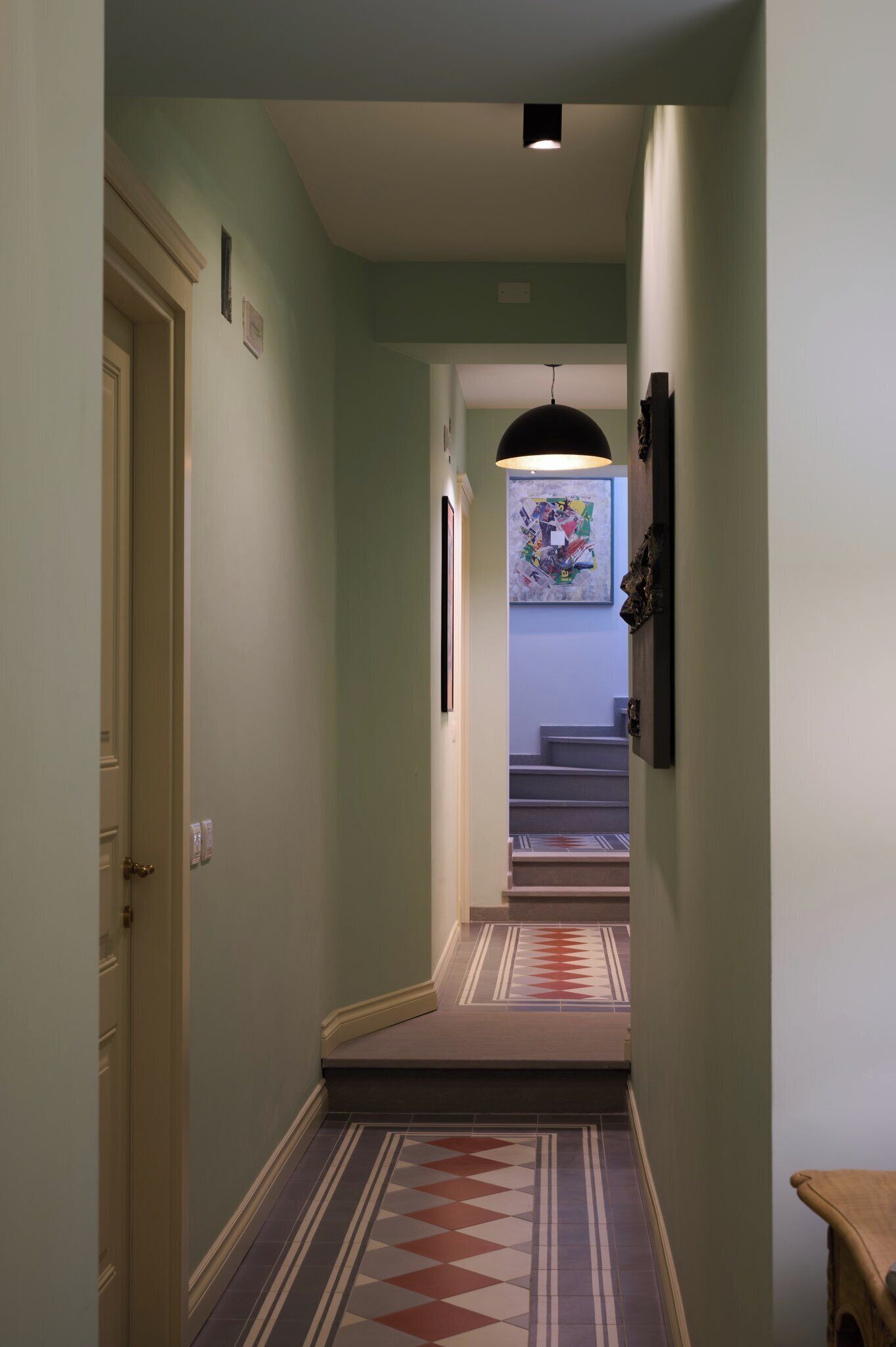 A narrow hallway with patterned flooring leading to a staircase.