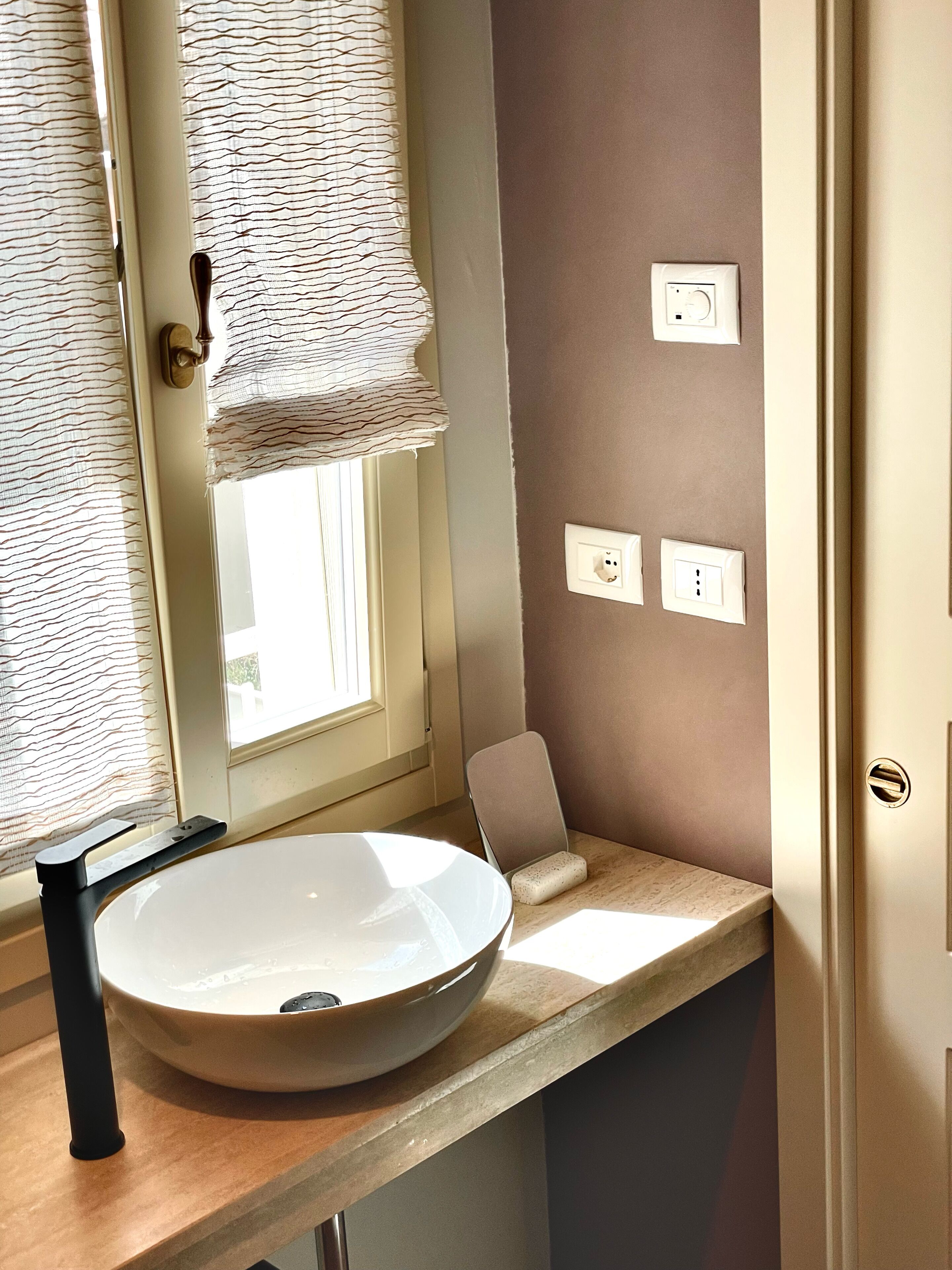 Un baño con un lavabo redondo, un perchero y una ventana con vistas.