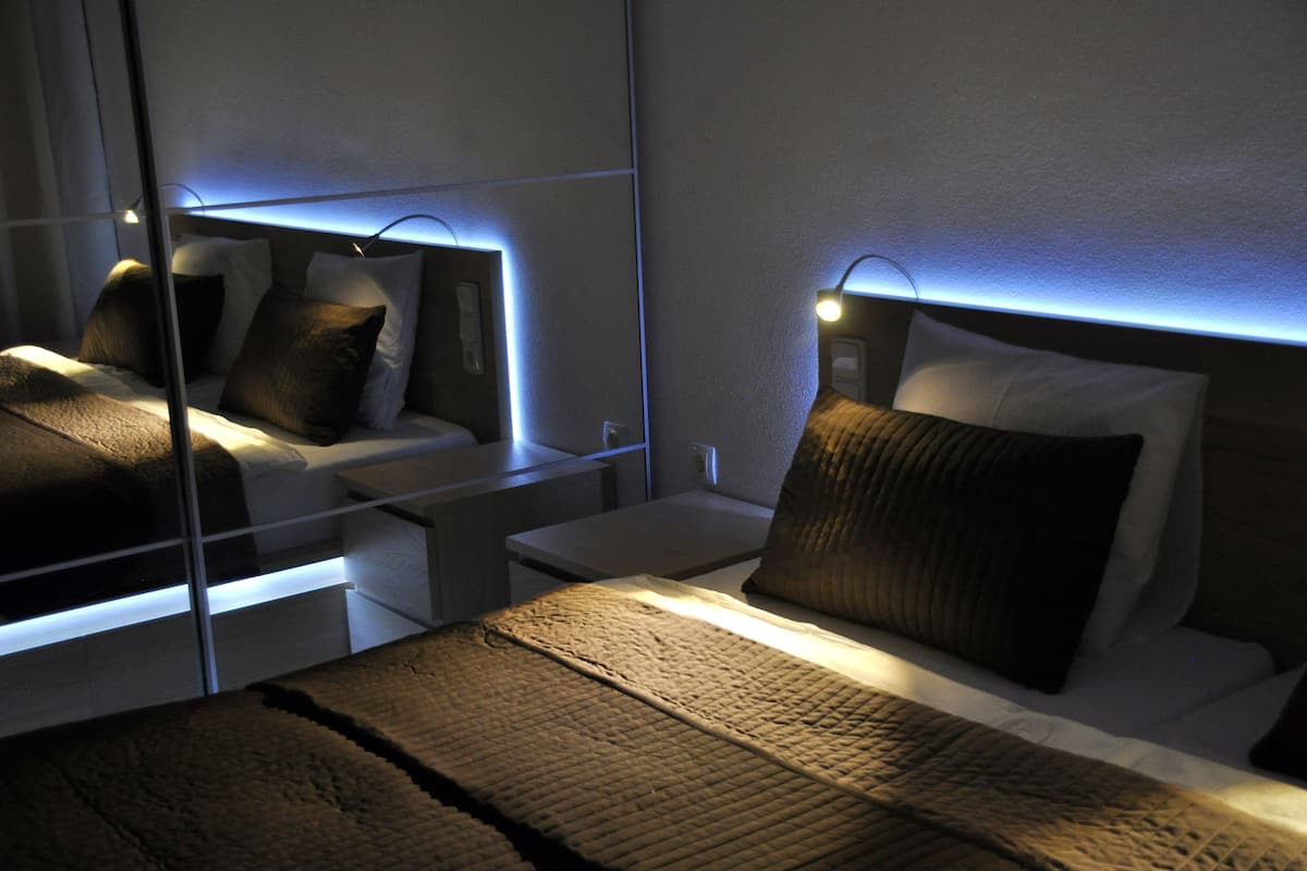A modern hotel room with a large bed, bedside tables, and a wall-mounted light fixture.