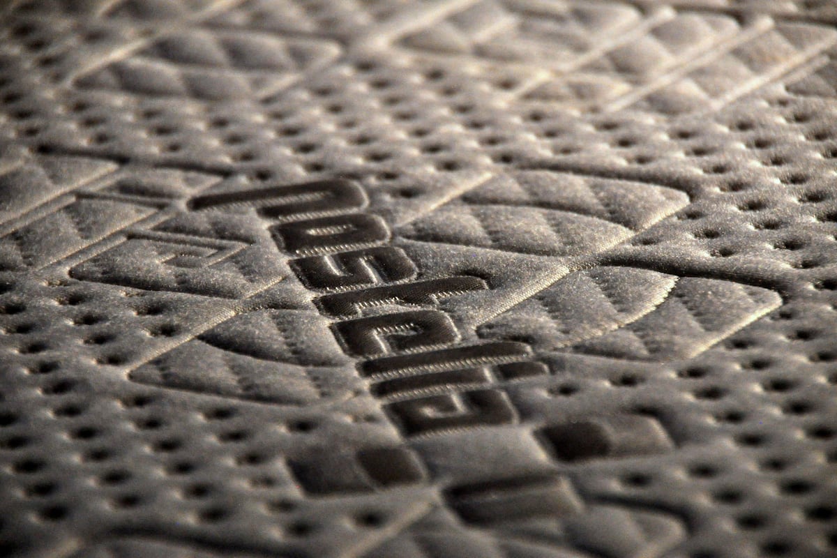 A close-up of a textured floor with a diamond pattern and embossed text.
