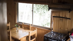 Un intérieur en bois comprenant une table à manger, des chaises et un poêle.