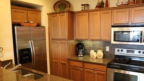 Una cocina con armarios de madera, un refrigerador de acero inoxidable, un microondas y un horno.