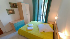 Un dormitorio con cama, armario, mesita de noche y luz en la pared.