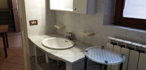 Un baño con lavamanos, tocador y una pequeña mesa redonda con superficie perforada.