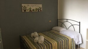 A bedroom with a bed, a wall-mounted artwork of cacti, and a bedside table. - Sapienza Time (Siena)