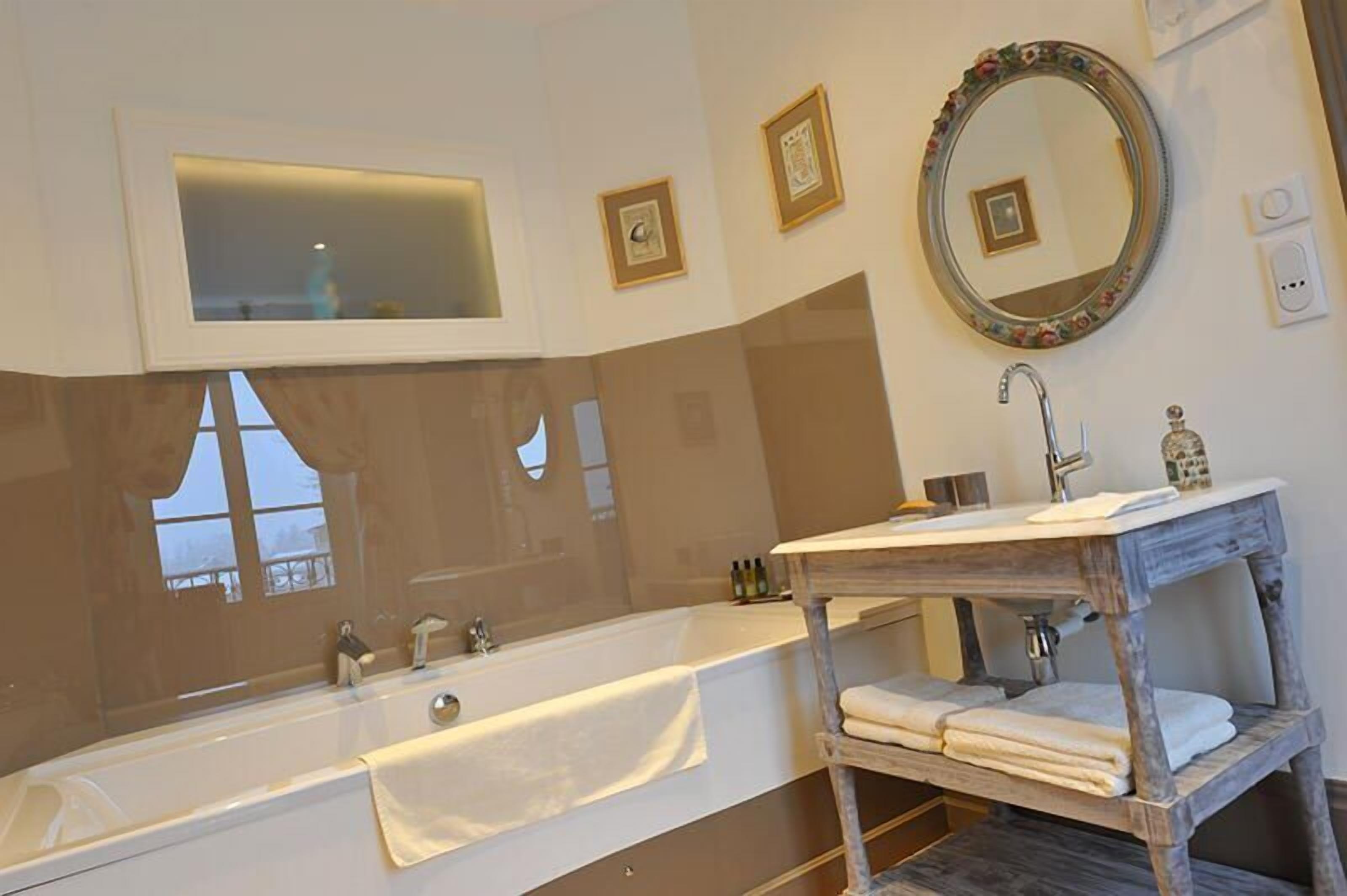 Une salle de bain moderne avec une grande baignoire, un meuble-lavabo en bois et un miroir doté d’un cadre décoratif.