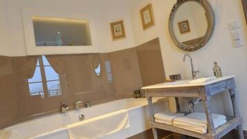 Une salle de bain moderne avec une grande baignoire, un meuble-lavabo en bois et un miroir doté d’un cadre décoratif.