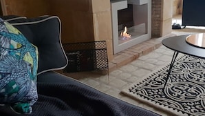 A living room with a fireplace, a sofa, and a patterned rug. - Nature & Chateaux à Azay le Rideau (Azay-le-Rideau)