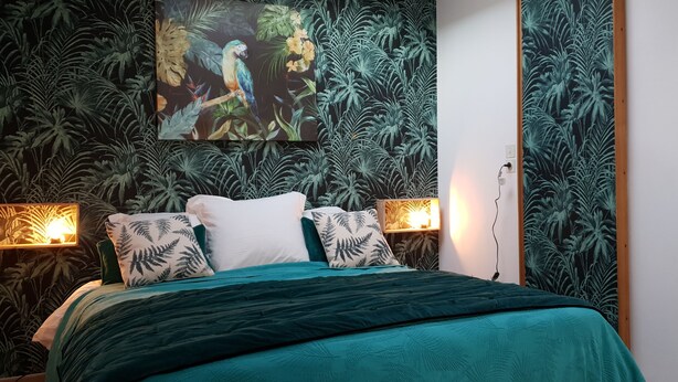 A bedroom with a bed, two wall-mounted lamps, and a painting of a parrot. - Nature & Chateaux à Azay le Rideau (Azay-le-Rideau)