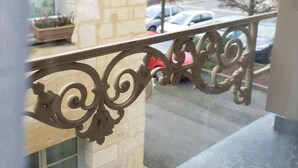 A balcony with ornate metal railings, a potted plant, and a view of parked cars and buildings in the background. - Nature & Chateaux à Azay le Rideau (Azay-le-Rideau)