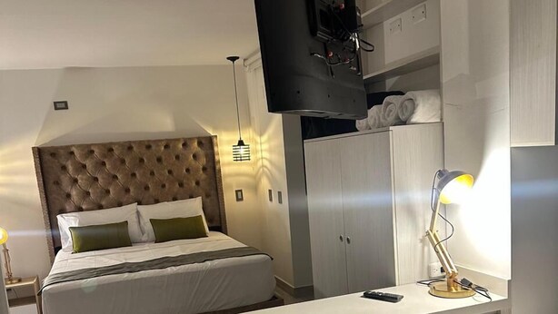 A modern hotel room with two beds, a TV mounted on the wall, a desk, and a wardrobe. - Hotel Balcones del Estadio (Medellín)