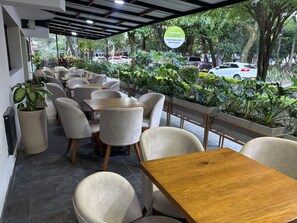 A restaurant with outdoor seating, potted plants, and a sign for 'Ayenda Hotel Balcones del Estadio.' - Hotel Balcones del Estadio (Medellín)