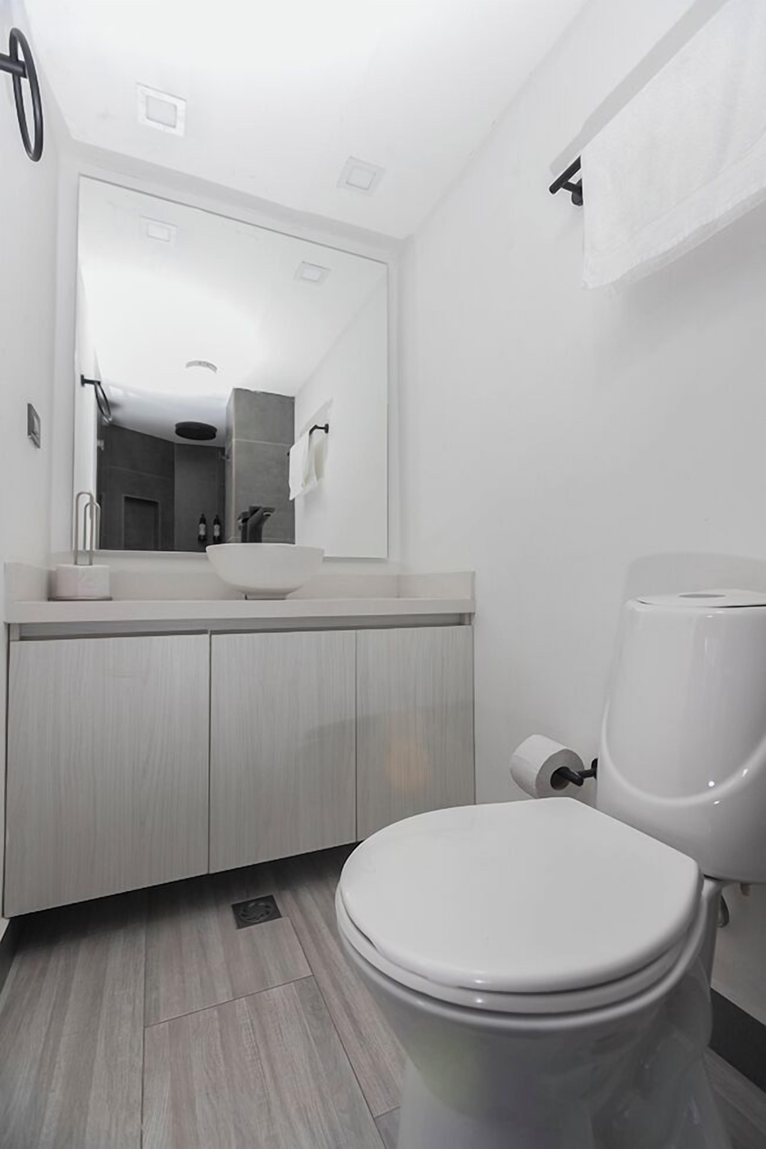 Une salle de bain moderne avec un lavabo, un miroir et des toilettes, le tout de couleur blanche.
