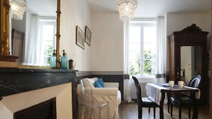 A room with a fireplace, a sofa, a dining table with chairs, and a chandelier. - Nature & Chateaux à Chinon (Chinon)