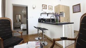 A compact living space with a kitchenette, a dining area with a bar stool, and a bedroom with a bed and dresser. - Nature & Chateaux à Chinon (Chinon)