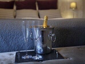 A metal bucket with a bottle of champagne and two empty glasses on a coaster.